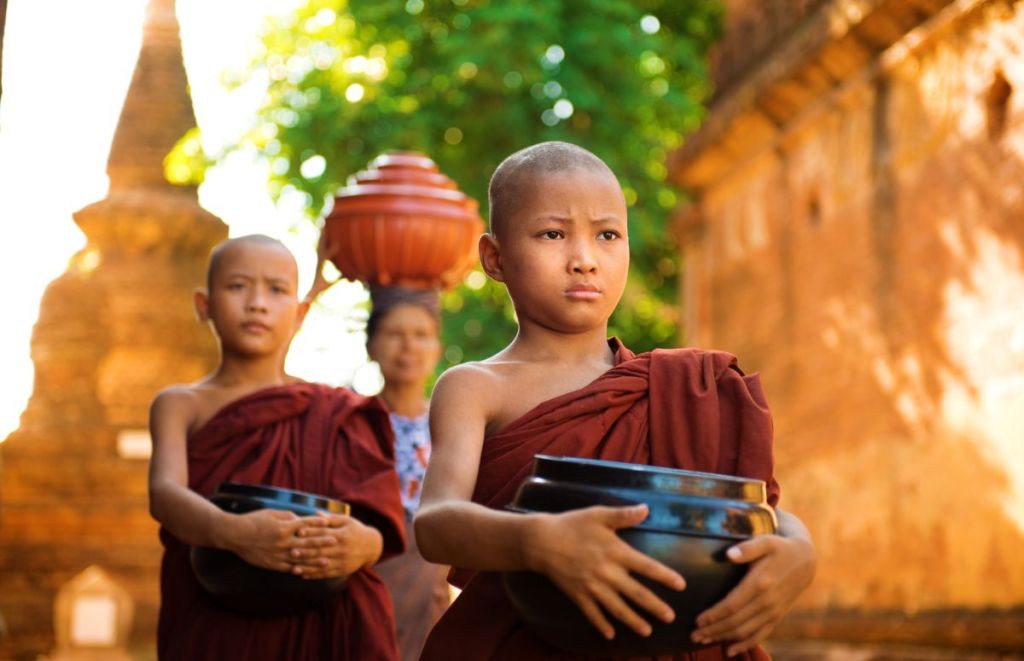 Young Buddhist monks carrying their eating bowls to a meal