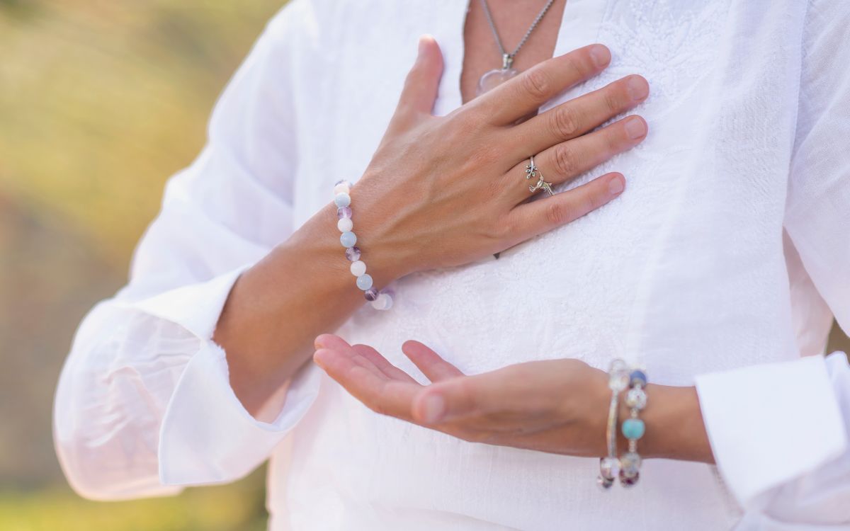 Closeup on a woman's chest with a hand over her heart, indicating self-acceptance