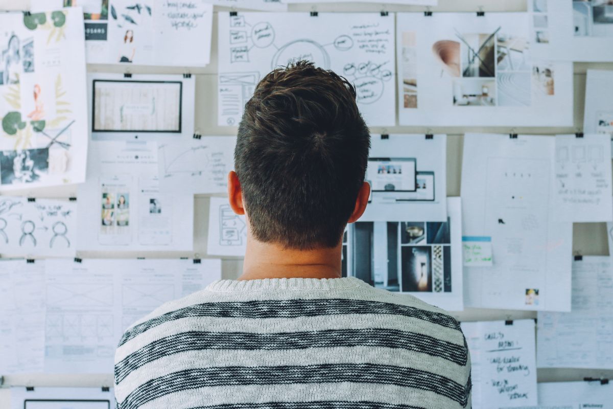 Rear view of a man staring at a wall filled with charts in careful consideration