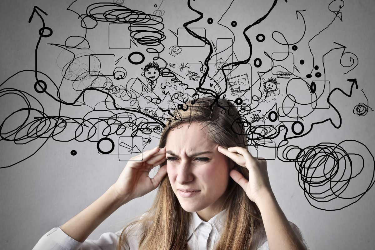 A woman with strained eyes touching her temples as illustrated squiggly lines and graphics emerge from her head, indicating a congested mind.