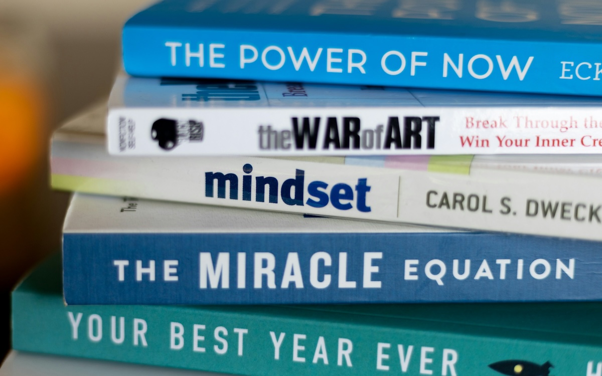 Close up cropped photo of a stack of self-improvement books on a table.